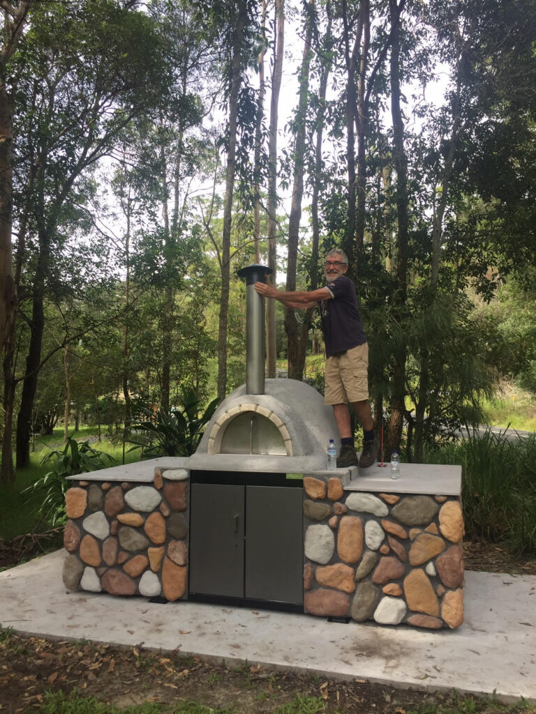 Man placing cap on pizza oven chimney