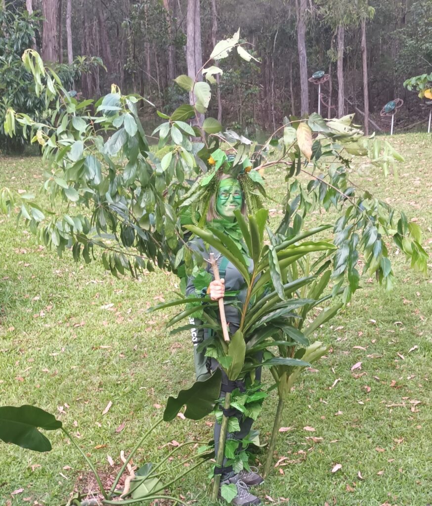 Woman dressed up to look like tree, covered in branches